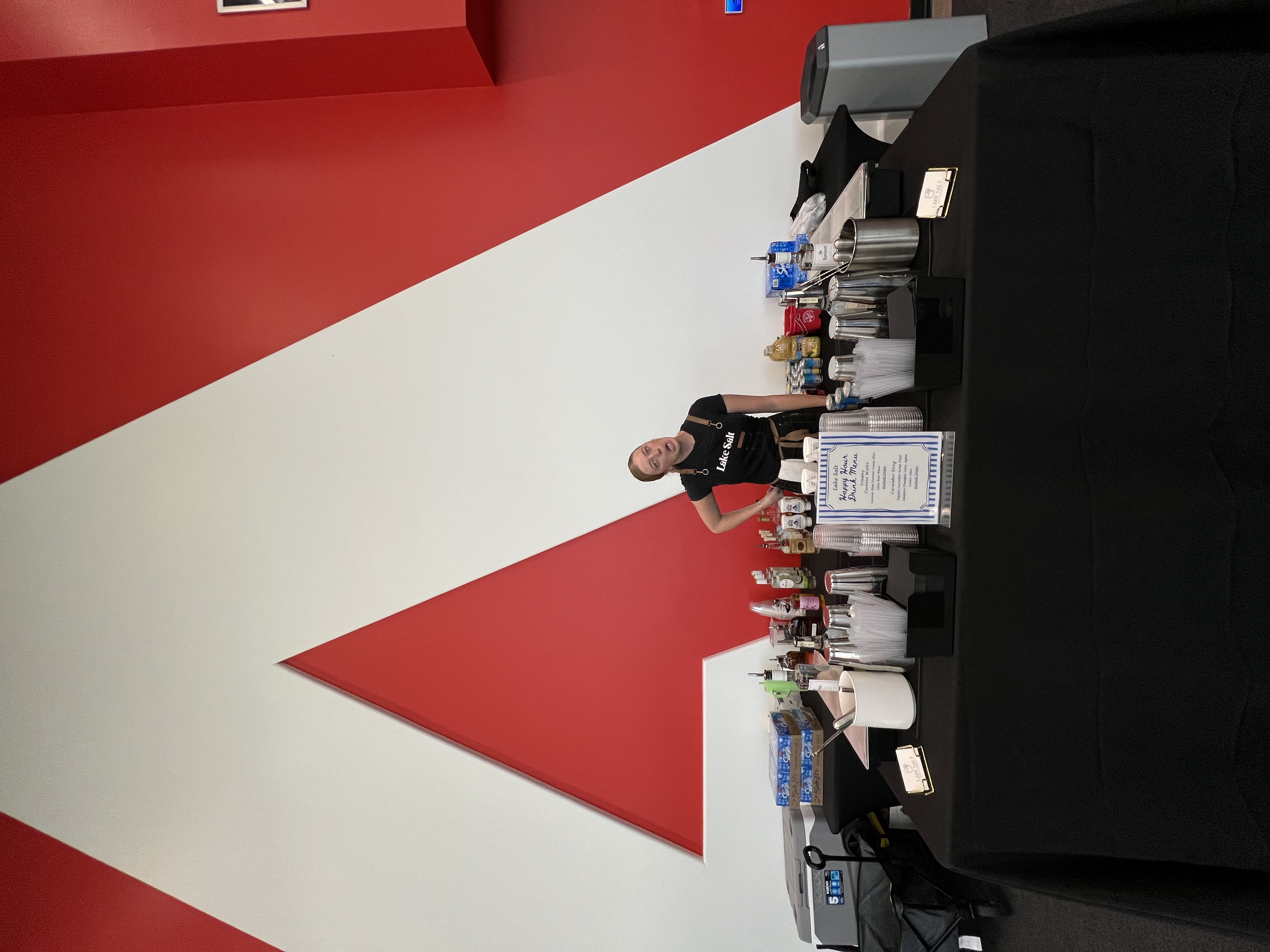 Lake Salt bartenders smiling behind a fully-stocked bar in front of the Adobe logo at Adobe Lehi